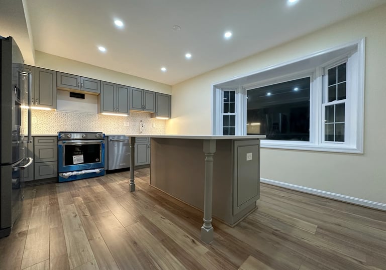 Kitchen renovation with grey cabinets, large island, and light brown LVP floor.