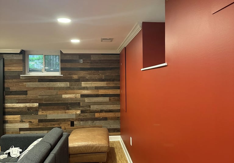 Renovated basement corner with reclaimed wood accent wall meeting deep red drywall and white crown.