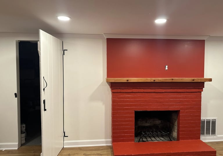 Freshly painted red brick fireplace with natural wood mantel against new matching red drywall.