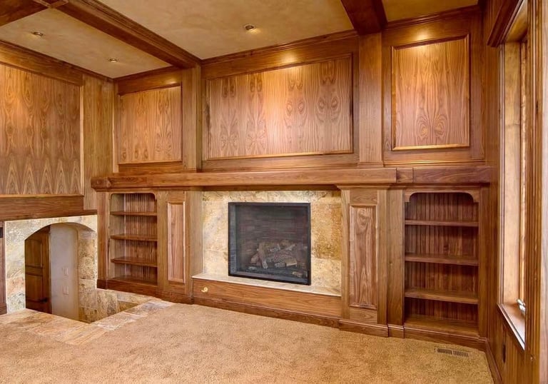 Custom walnut wood wall paneling with built-in bookshelves and fireplace mantel in a library.