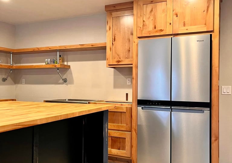 Rustic kitchen with wood cabinets, butcher block island, and stainless steel French door refrigerator.