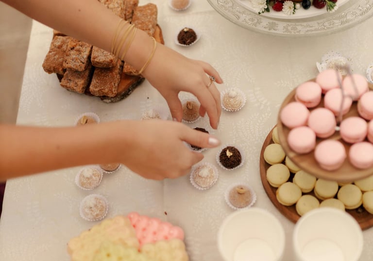 Mesa de postres elegante con un pastel estilo naked cake con frutos rojos y macarons rosas