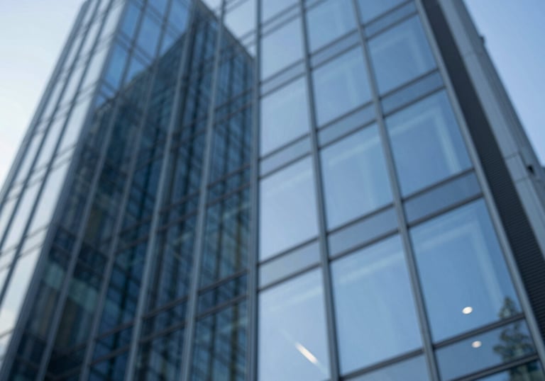 A low-angle shot of contemporary architectural glass reflecting a blue sky, symbolizing innovation and strategic clarity, incorporating #4B6587.