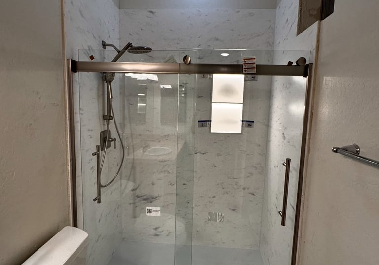 Modern bathroom remodel featuring a walk-in shower with sliding glass doors and marble wall panels.