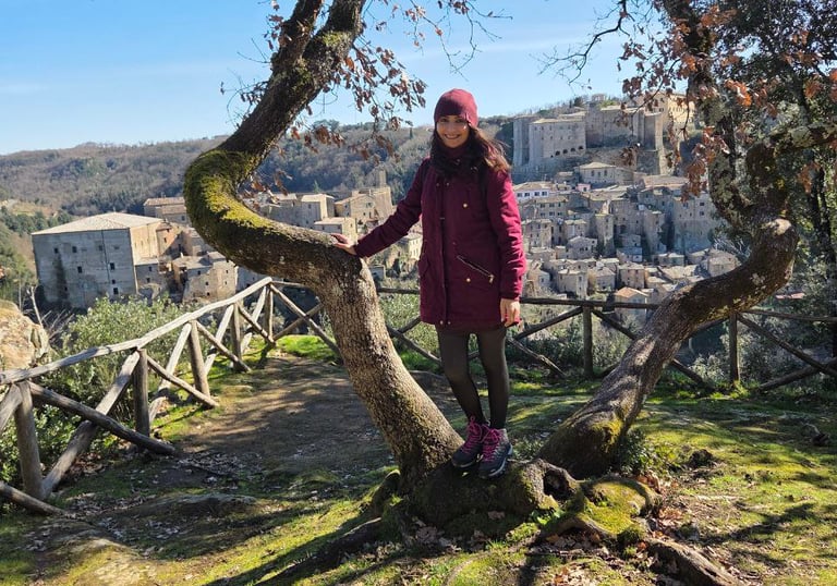 Donna sorridente in un prato di montagna appoggiata a un albero