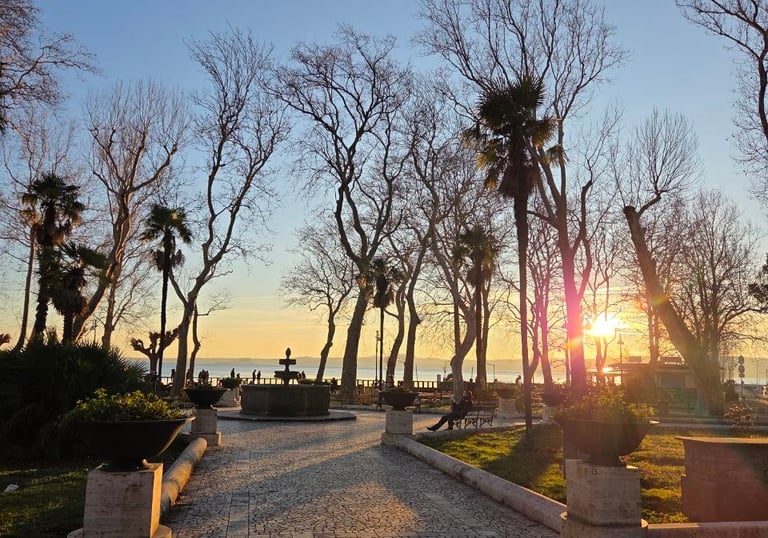sentiero di pietra che conduce al mare al tramonto con alberi ai lati