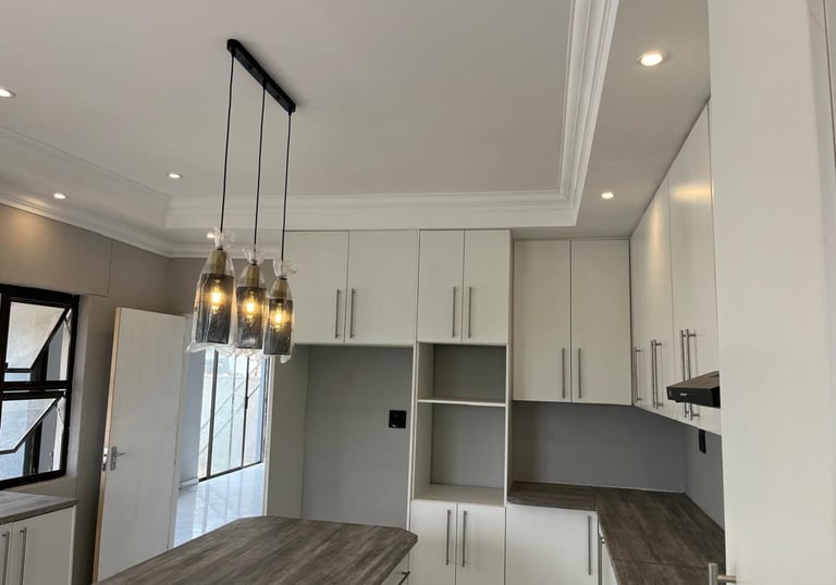 a kitchen with a wooden table and a bar stool, House Construction Frans-del Investment CC Constructi