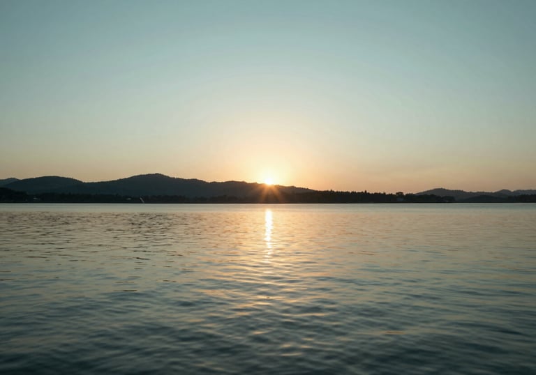 A peaceful outdoor scene of a sunset over a calm lake, representing a worry-free retirement. High-quality photography with soft #B8D3E7 and #4A7C59 color tones.