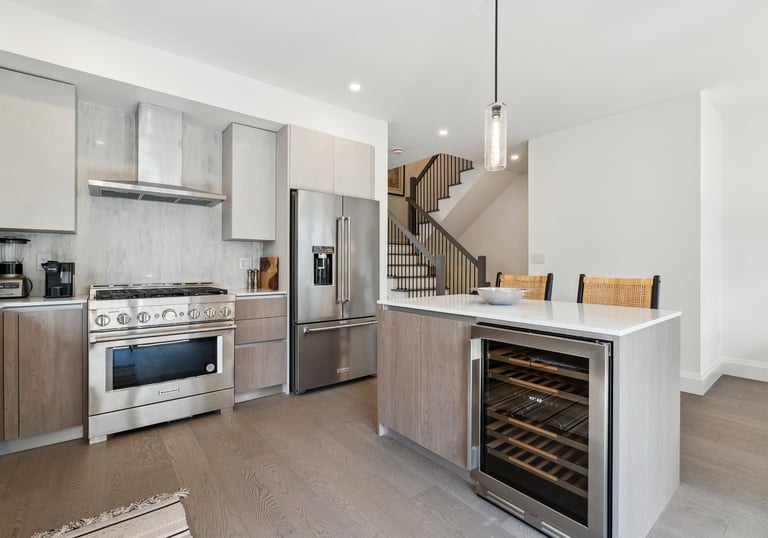 Modern luxury kitchen with stainless steel appliances, marble backsplash, and a kitchen island featuring a built-in wine