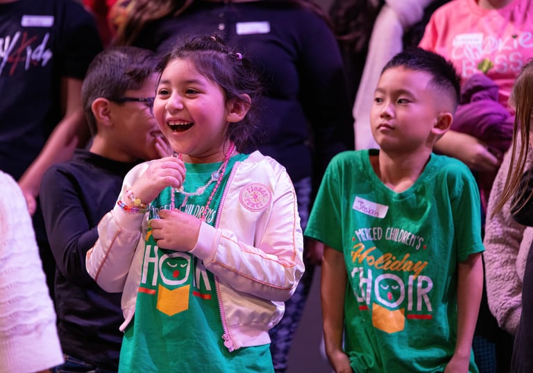A happy young girl laughing during a performance with the Merced Children's Holiday Choir.