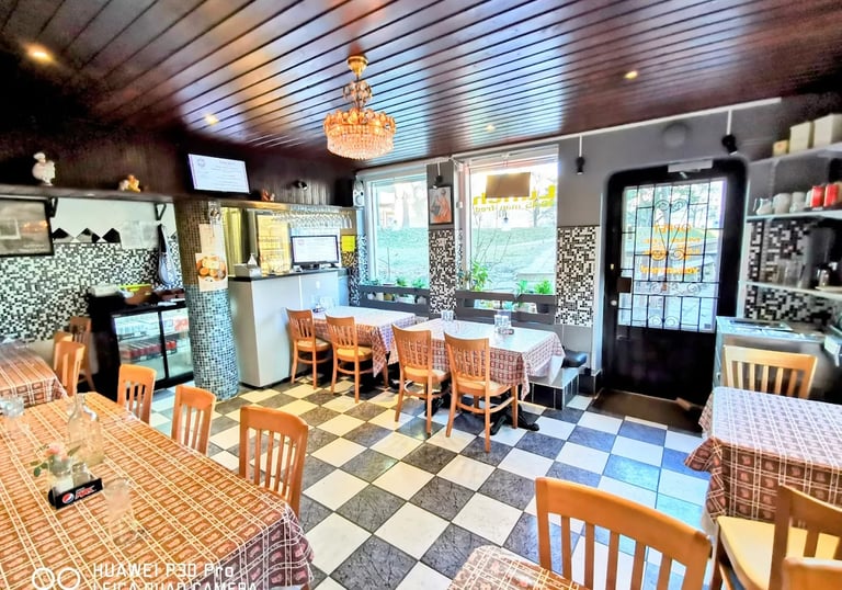 Cozy restaurant interior featuring checkered floors, wooden tables, and a vintage crystal chandelier.
