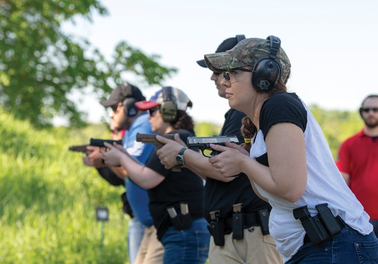 People outdoors training in the defensive use of firearms