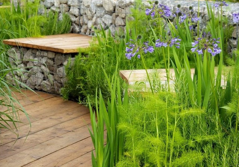 Decking area with stone seating topped with wooden benches, finished with green plants around the ed