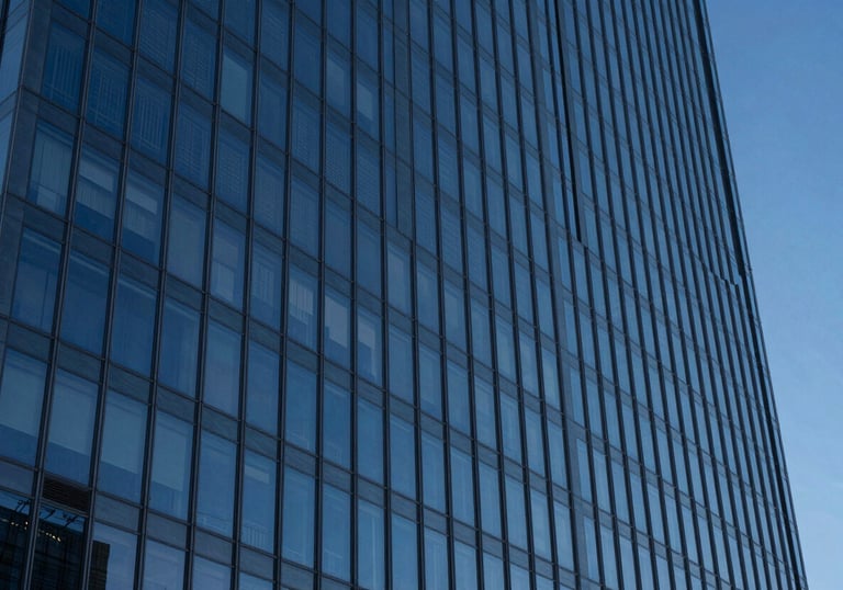 A professional photography shot of a sleek glass skyscraper reflecting a deep blue evening sky. Sharp lines, minimalist composition. Global / High-end corporate.