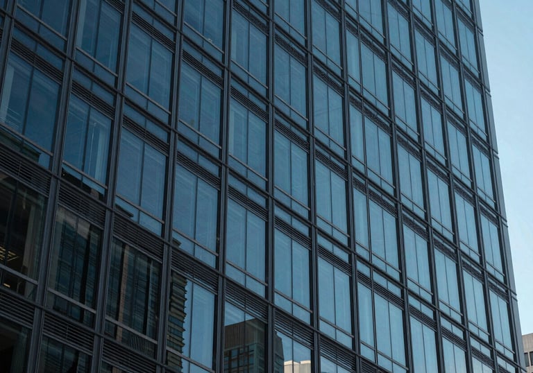 A close-up of a modern North American / US office building facade made of glass and steel, reflecting the blue sky.