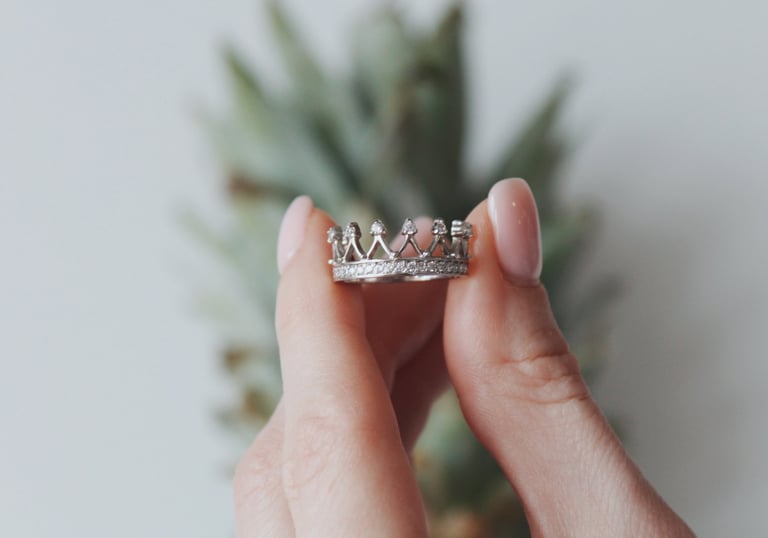 a woman's hand holding a ring with a crown
