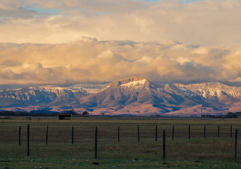 a large mountain range with a fenced in area, located in Montana, Teton Mountain Range