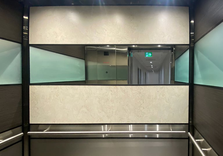 elegent elevator interior with cream and brown wall panels, a mirror and round handrails