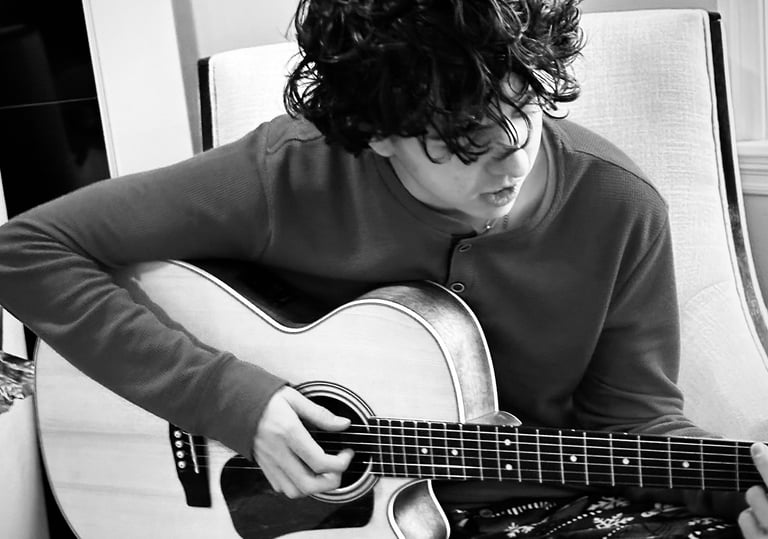 a man playing guitar in a chair black and white