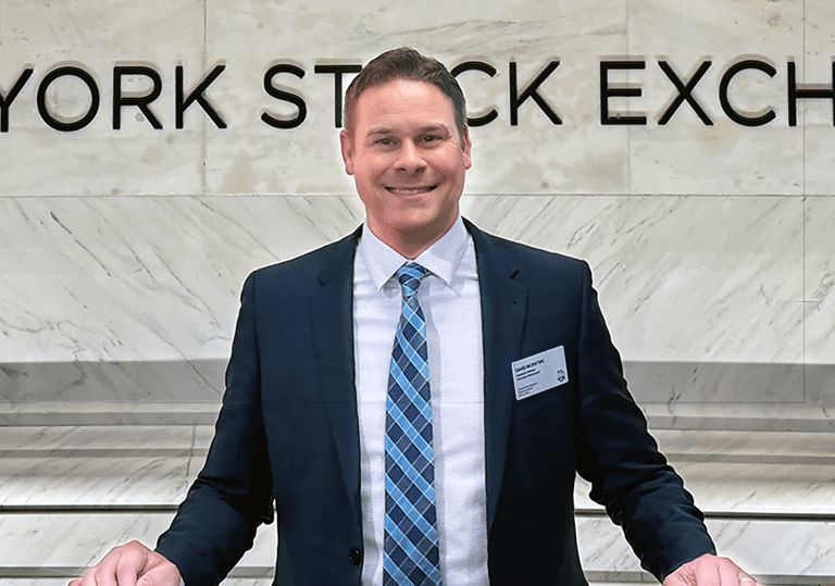 a man in a suit and tie standing in front of a sign that says new