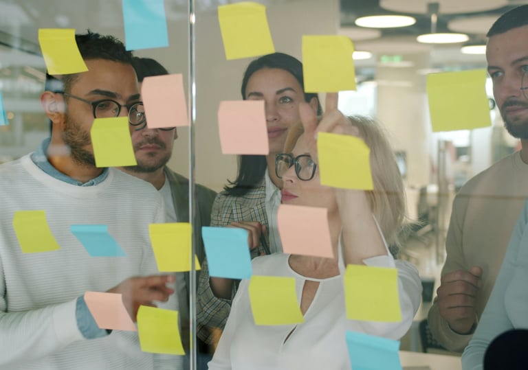 equipo de trabajo ordenando post-it sobre pared de cristal