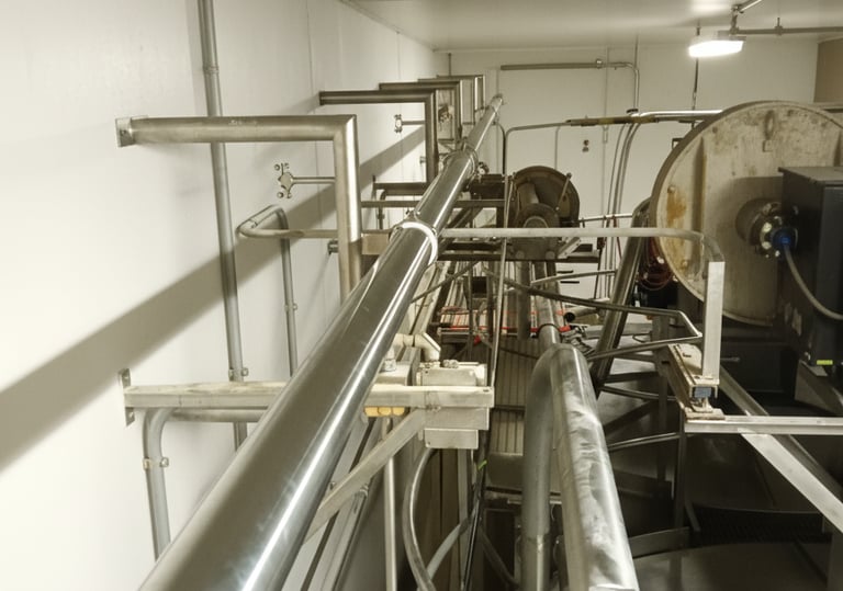 Industrial stainless steel hangers and piping and prong equipment in a production facility.