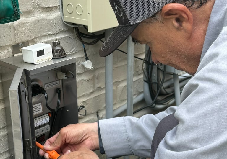 Electrician installing low voltage landscape lighting transformer for outdoor lighting system.