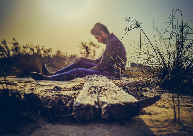 homme, assis dans la nature, en prise avec un mal-être