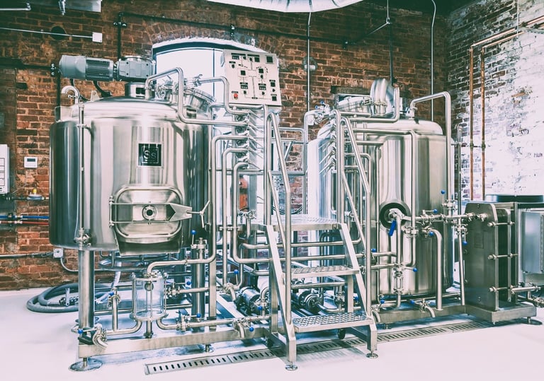 Industrial stainless steel brewery equipment and fermentation tanks inside a modern craft brewery facility.