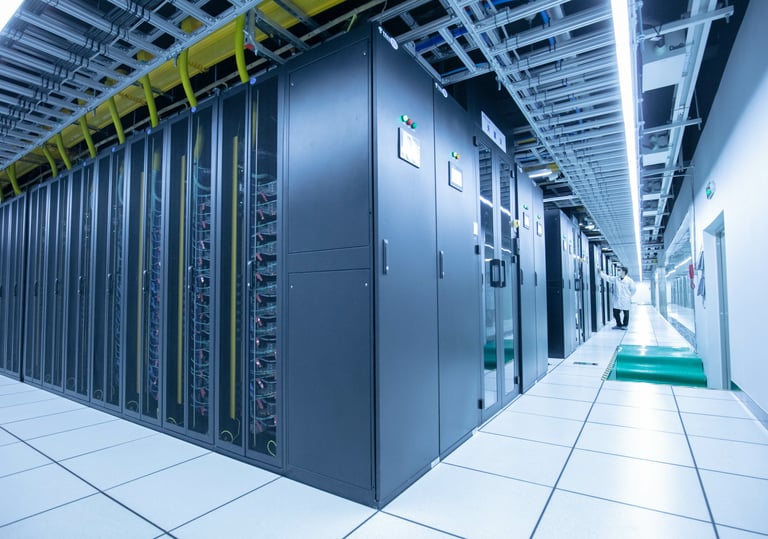 A technician inspects rows of black server racks in a modern data centre.