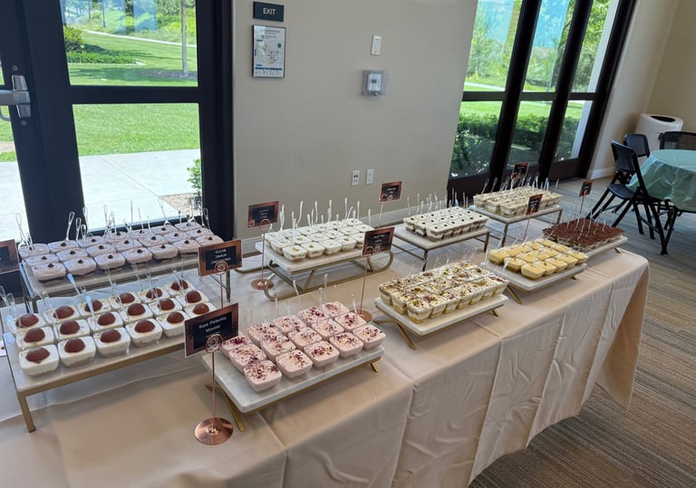 Indian Desert cups for a catering event laid out on a table. With gulab jamun, mousse, etc.