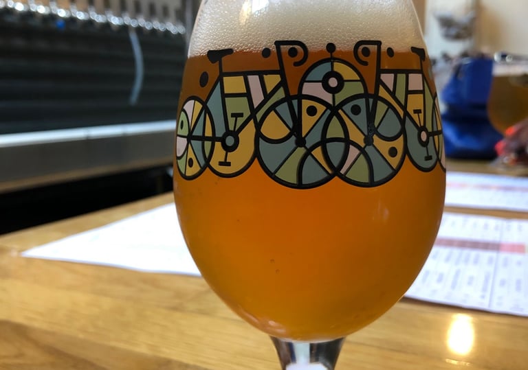 Craft beer in a tulip glass with bicycle art at a brewery taproom.