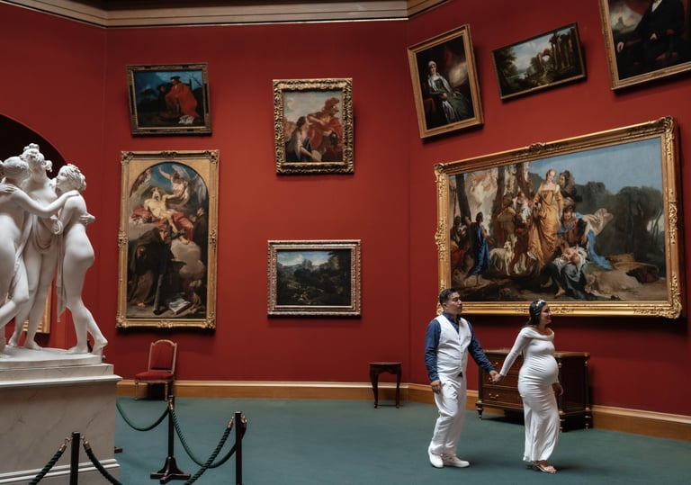 A pregnant couple holding hands walks through an art gallery with red walls and classical oil paintings.