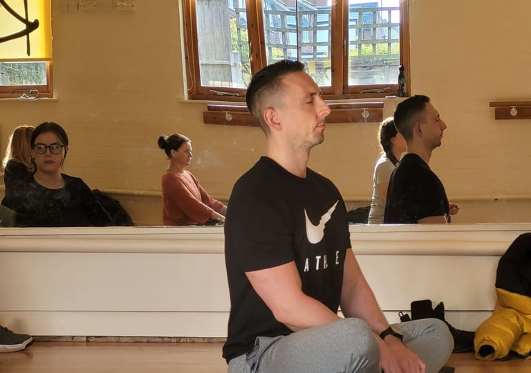 A man sat up straight meditating in a yoga class