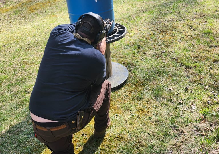 Man using Self-defense firearm (Carbine) kneeling from behind a barrier on training range.