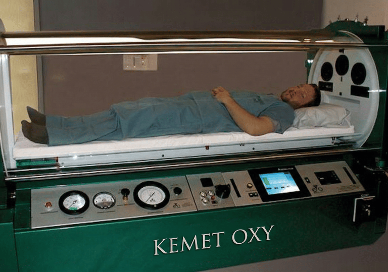 A patient lies inside a Kemet Oxy monoplace hyperbaric oxygen therapy chamber for medical treatment.
