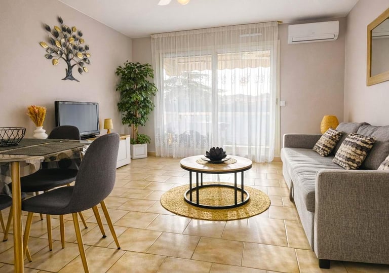 Salon moderne avec un canapé gris, une table basse ronde et une grande porte coulissante et rideaux