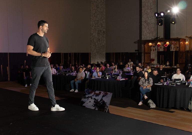 Fotografía de eventos en Cancún. Conferencista Oso Trava exponiendo sobre escenario en salón corporativo.