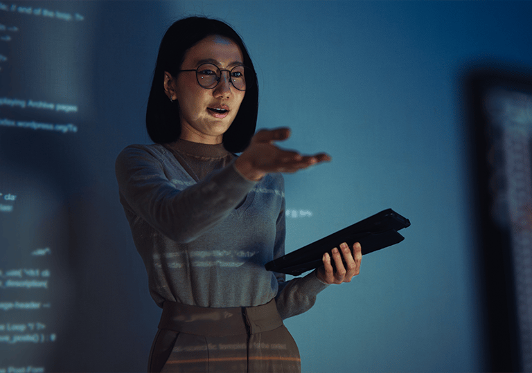Instructor presenting on a tablet with code projected on a screen in the background