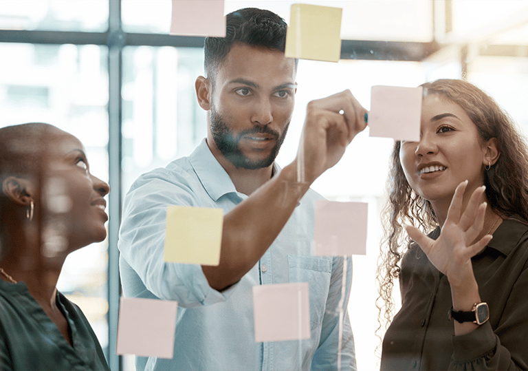 Diverse team brainstorming with sticky notes on glass wall during a strategy session