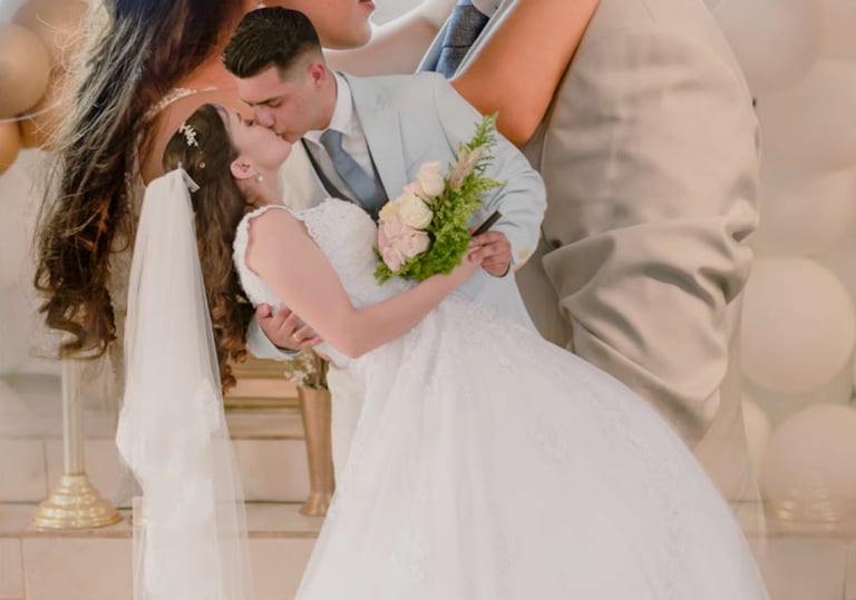 a bride and groom kissing in front of a neon sign