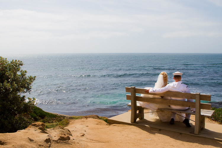 couple sitting on bench overlooking blue ocean at cuvier park
