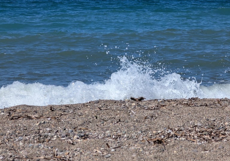 waves crashing on the sandy beach of Paralia Petra in Petra, Greece