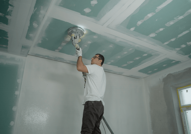 a man is painting a ceiling with a ceiling fan
