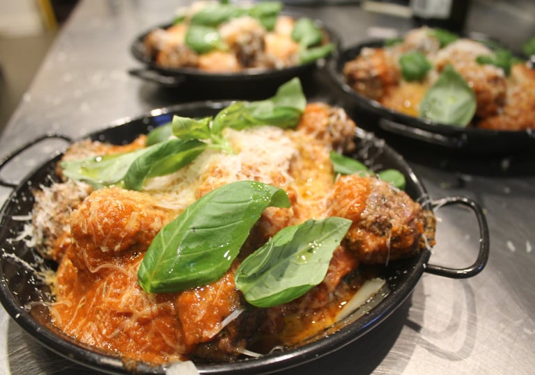 a pan of meatballs with basil sauce