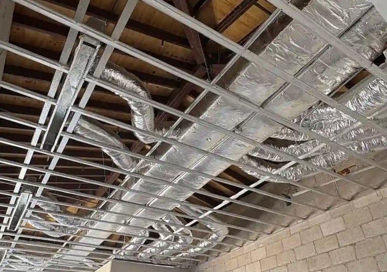 Ductería HVAC residencial con aislamiento plateado instalada en entretecho