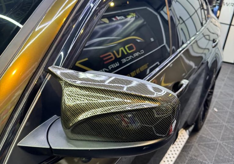 Car side mirror wrapped in carbon fiber vinyl partial wrap