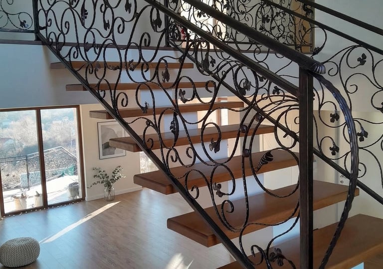 Modern floating wood staircase featuring custom ornate wrought iron railings and banisters.