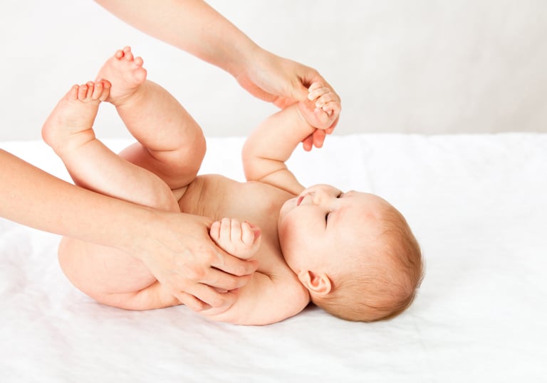a baby is laying on a bed with a woman's hands