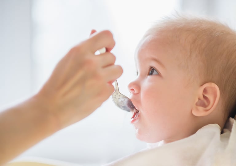 a baby is gets food with a spoon